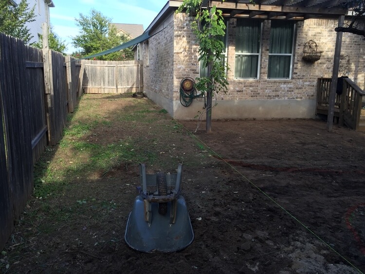 overturned wheelbarrow in an unfinished backyard