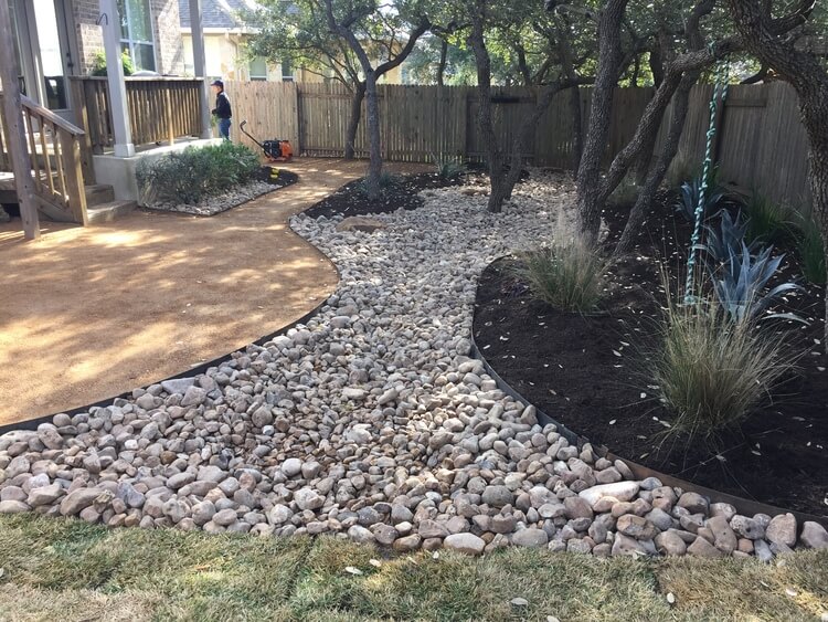 landscaping with a section of gravel, a section of pebbles, and a sections of grass.